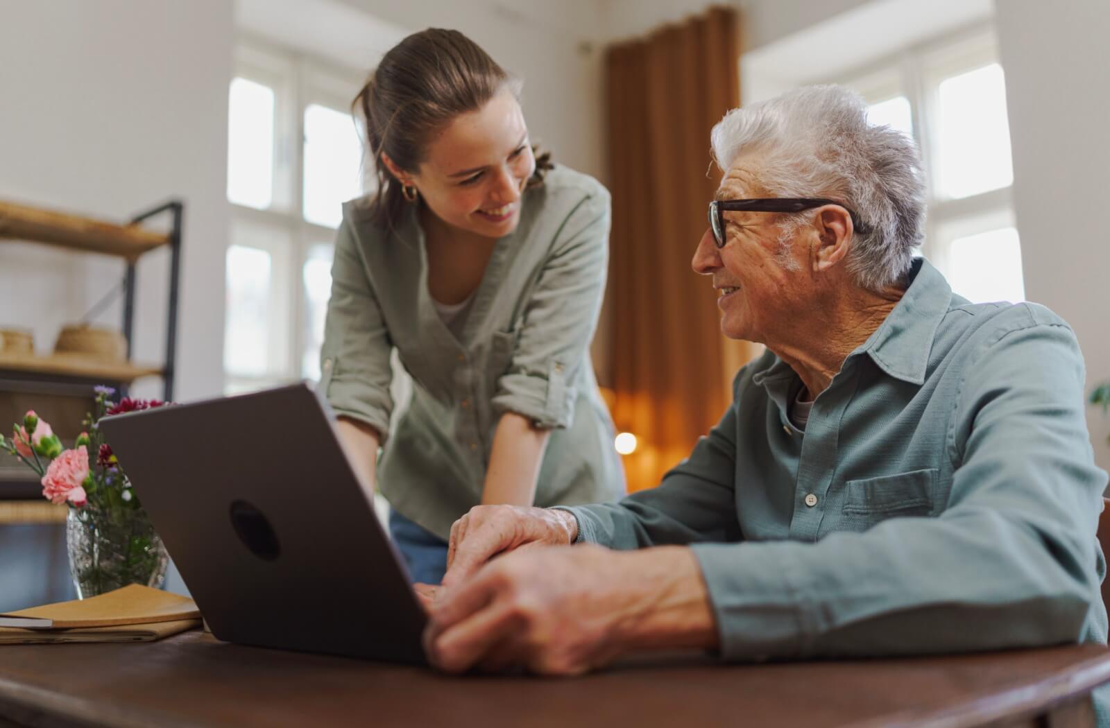 A senior looking at assisted living community options online with their adult child.