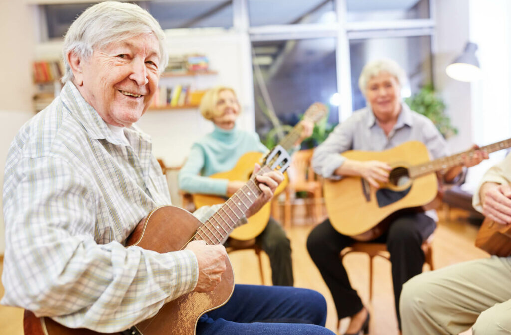 A group of seniors smiling with guitars while on a day trip to learn to play instruments.