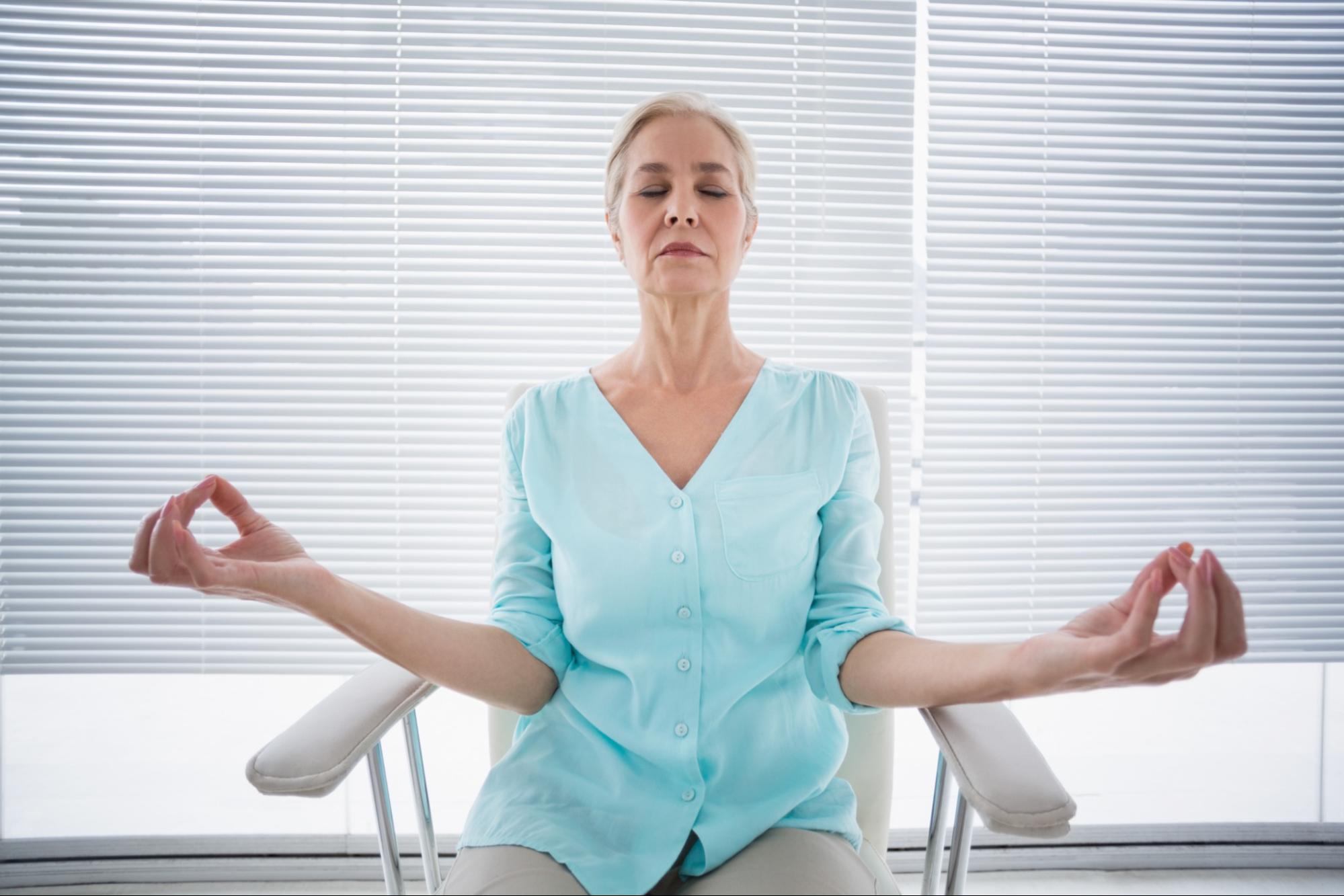 A senior woman doing chair yoga.