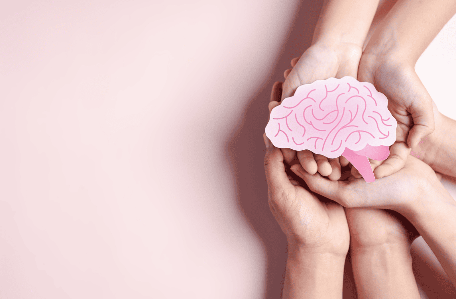 Hands hold a paper cut out of a pink brain.