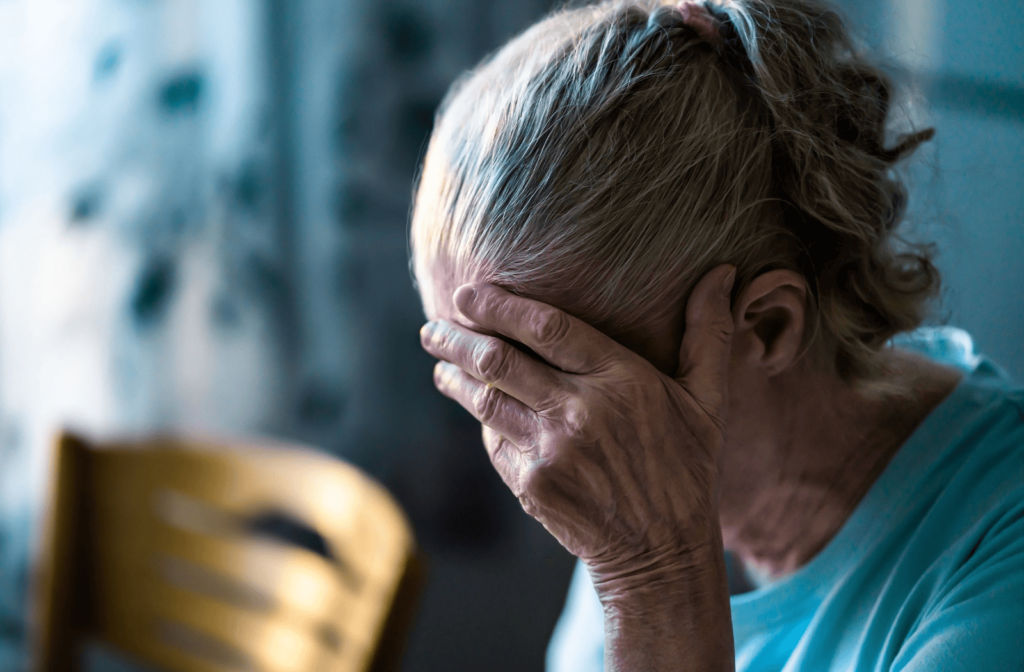 A senior holds her head with her hand.