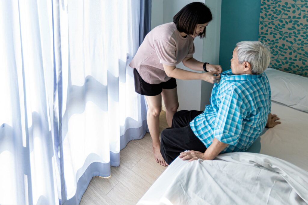 Memory care staff helping a resident get dressed/undressed.