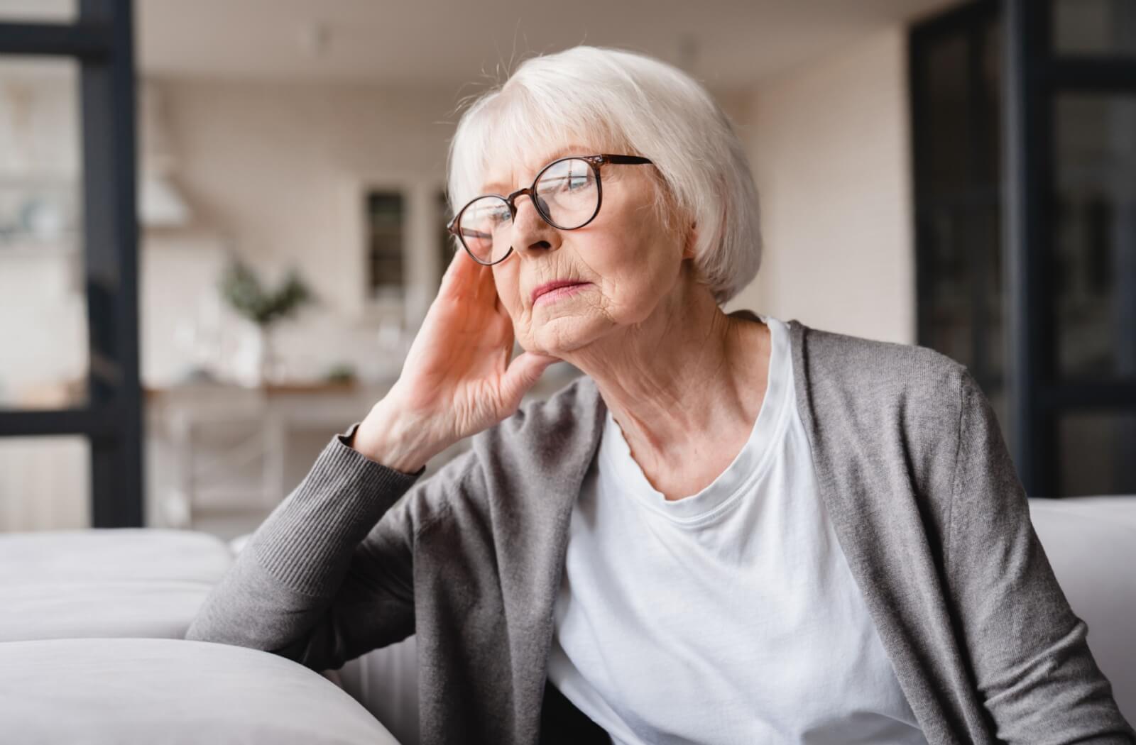 A senior struggling with memory loss gazing out the window with a contemplative expression