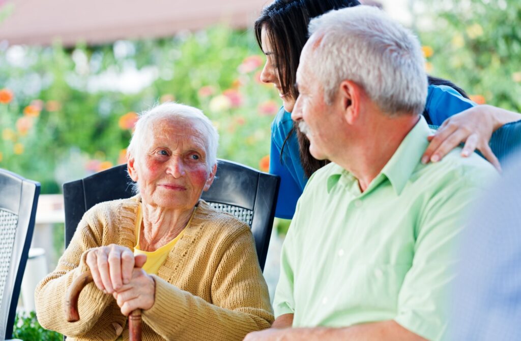 : Adults and staff at a memory care community sitting together outdoors.