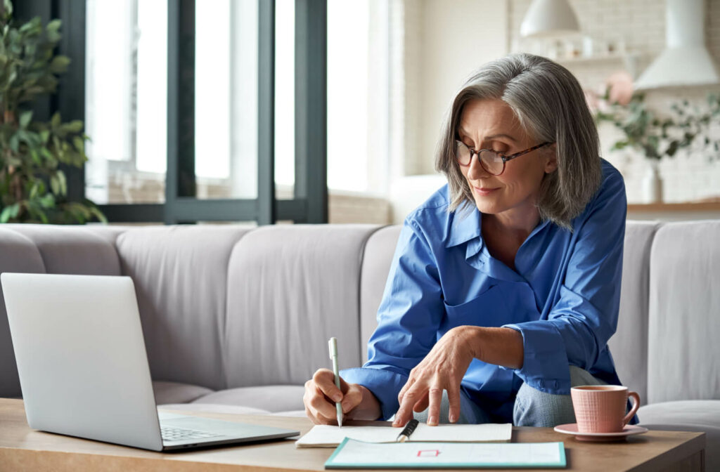 a senior woman does paperwork sitting on a couch