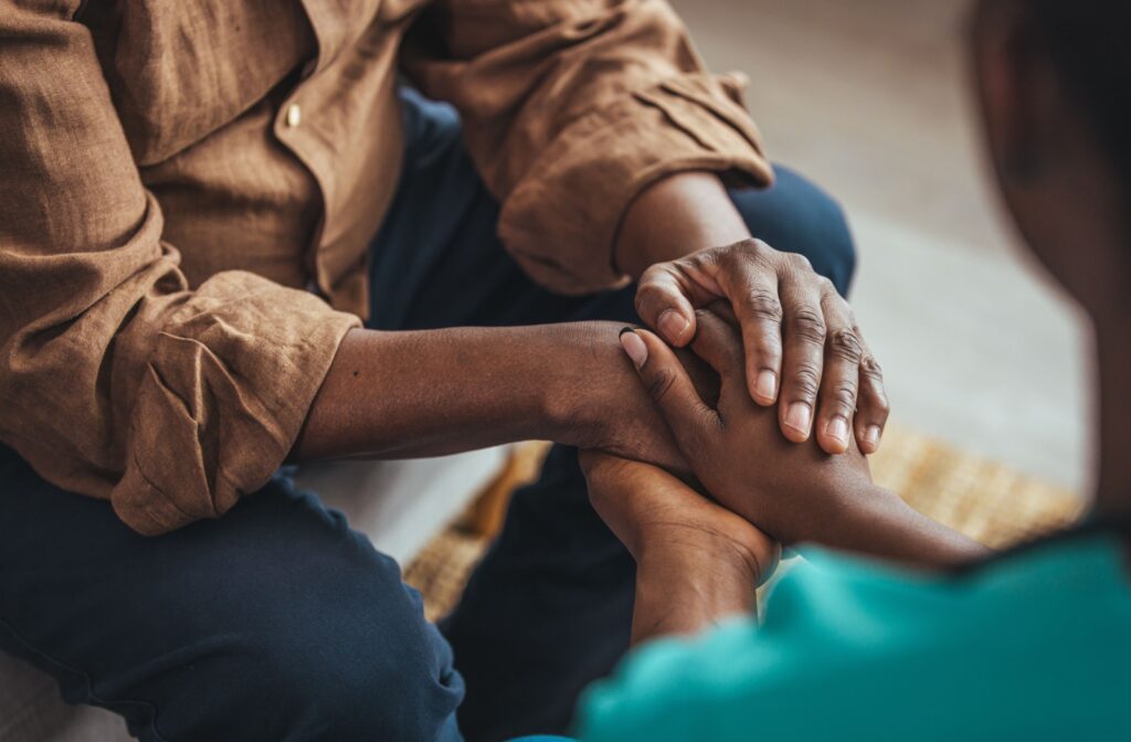 young person holding the hands of a senior with dementia in support